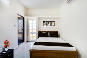 A bedroom with a bed, a nightstand, a window with curtains, and a wall with three framed pictures. - Super Collection O Sholinganallur (Chennai)