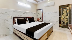 A hotel room with a bed, a mirror, a door with a floral design, and a ceiling fan. - Hotel O Eluru Railway Station (Eluru)