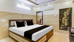 A hotel room with a bed, a ceiling fan, an air conditioning unit, a mirror, and a decorative door. - Hotel O Eluru Railway Station (Eluru)