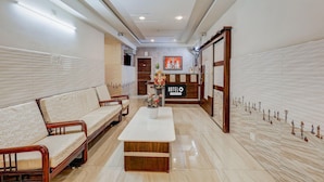 A hotel lobby with a reception desk, a sofa, a coffee table, and a decorative wall. - Hotel O Eluru Railway Station (Eluru)