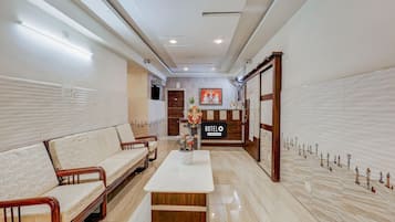 A hotel lobby with a reception desk, a sofa, a coffee table, and a decorative wall.