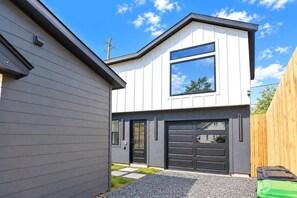 Ein modernes, zweistöckiges Haus mit Garage, großem Fenster und Holzzaun.