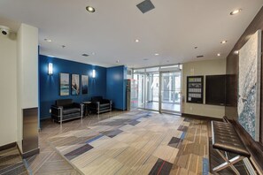 A lobby with a blue wall, seating area, and a reception desk. - THE COSMOPOLITAN- YXE Penthouse (Saskatoon)