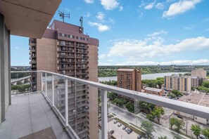 Um edifício alto com várias varandas, um rio ao fundo e céu claro.