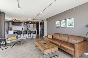 A modern living space with a kitchen, dining area, and seating. - THE COSMOPOLITAN- YXE Penthouse (Saskatoon)