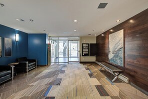 A modern lobby with a patterned carpet, a reception desk, and a bench. - THE COSMOPOLITAN- YXE Penthouse (Saskatoon)