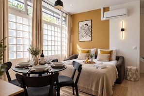 A hotel room with a bed, a dining table set for two, and a large window with curtains. - TheBlueStay 365 - Beautiful A/C Apartment in Paris (Paris)