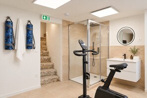 A modern bathroom with a glass shower enclosure, a standing exercise bike, a white sink, and a mirror. - TheBlueStay 365 - Beautiful A/C Apartment in Paris (Paris)