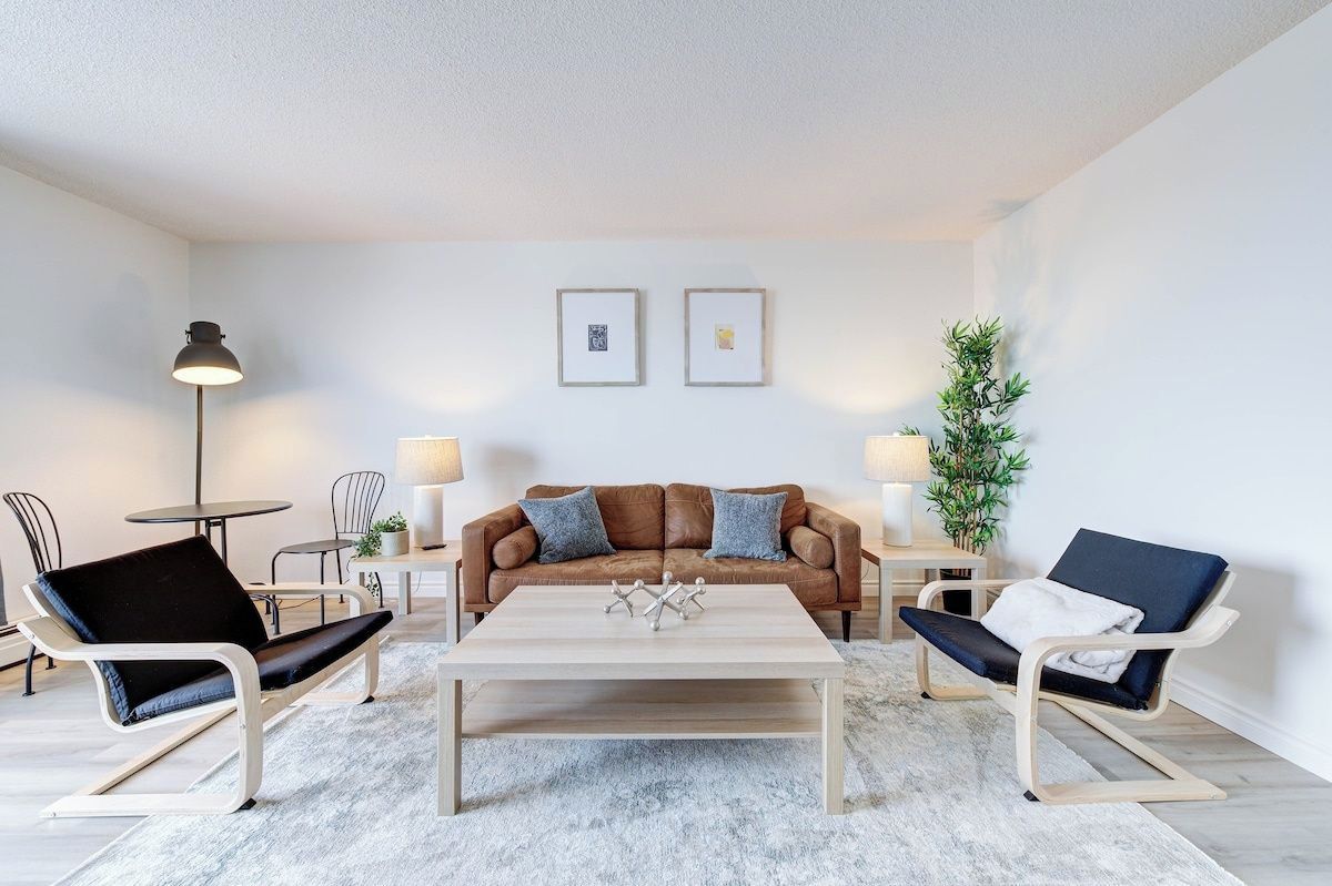 A modern living room with a brown leather sofa, two armchairs, a coffee table, and a floor lamp.