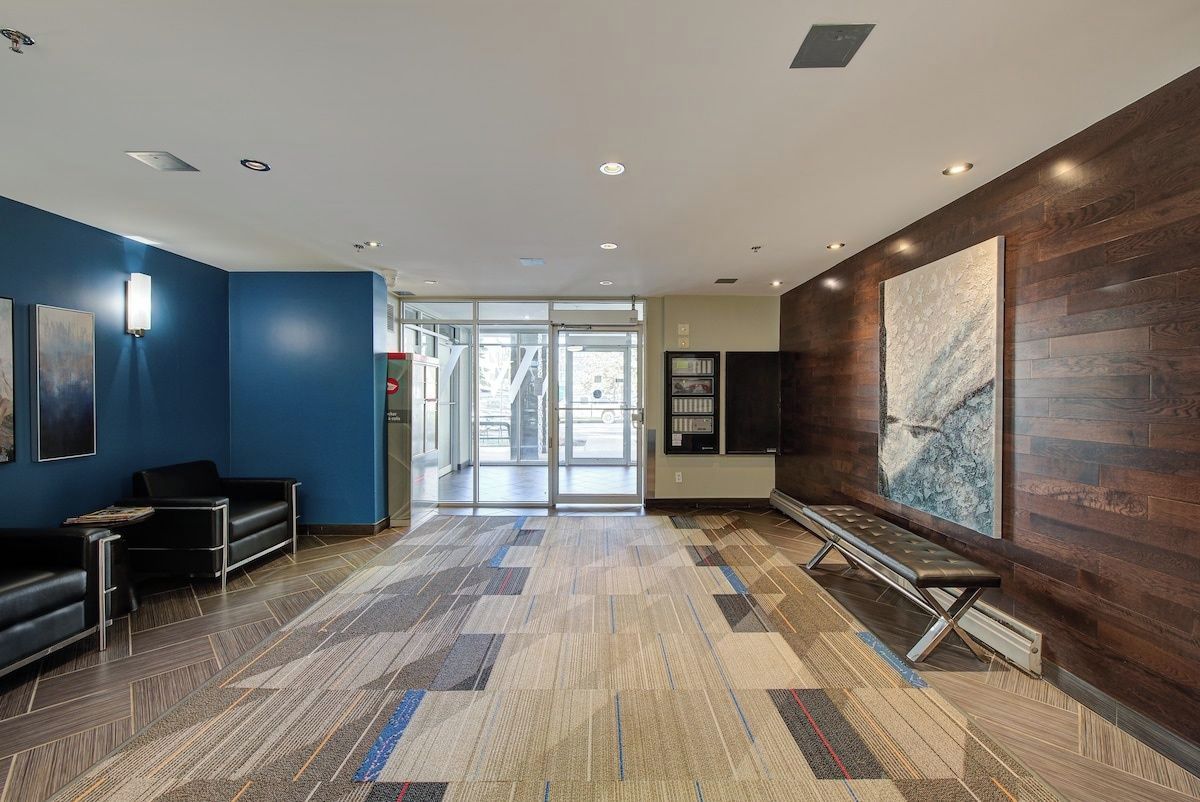 Un hall d’entrée moderne avec un tapis à motifs, un comptoir d’accueil et un grand tableau abstrait accroché au mur.