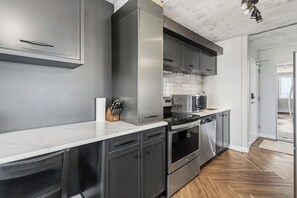 Eine moderne Küche mit Edelstahlgeräten, einer Marmorarbeitsplatte und Holzboden.