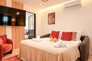 A modern hotel room with a bed, a TV, and a wall-mounted air conditioner. - TheBlueStay 366 - Beautiful A/C Apartment in Paris (Paris)