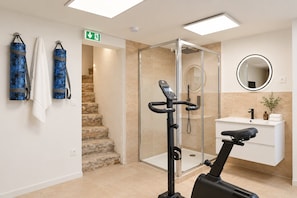 A modern bathroom with a glass shower enclosure, a standing exercise bike, a white sink, and a mirror. - TheBlueStay 366 - Beautiful A/C Apartment in Paris (Paris)