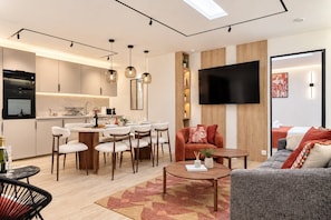 A modern living room with a dining area, a flat-screen TV mounted on the wall, and a kitchen with a built-in oven. - TheBlueStay 366 - Beautiful A/C Apartment in Paris (Paris)