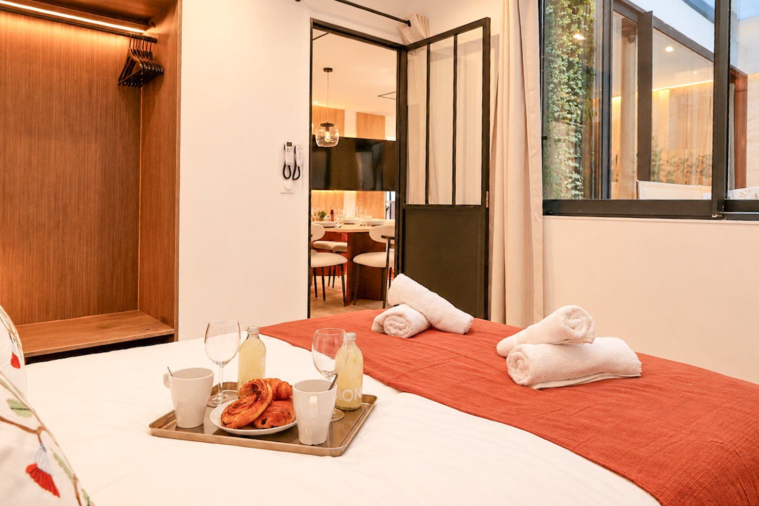 A hotel room with a bed, a breakfast tray, and a view of the dining area.