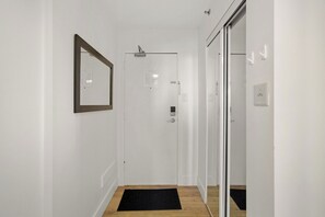 Ein Flur mit einer Tür, einer schwarzen Matte, einem gerahmten Bild und einem Lichtschalter an der Wand.