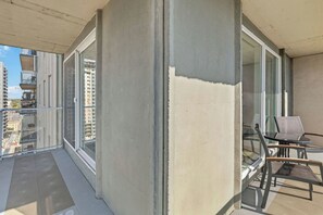 Ein Balkon mit Glastür, einem Sessel und einem Tisch.