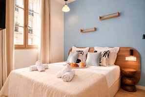 Ein ordentlich bezogenes Bett mit Handtüchern, einem Frühstücksbrett und einem Nachttisch mit Lampe.