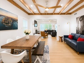 Una sala de estar moderna con una mesa de comedor de madera, un sofá azul y un cuadro grande con una vista de la ciudad.