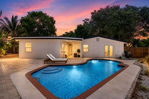 Una casa moderna con piscina, patio y zona exterior cubierta.