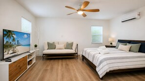 Un dormitorio con cama, sofá, televisión y ventilador de techo.