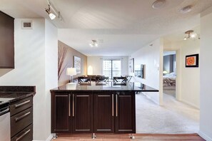 Een moderne keuken met donkere kastjes, een centraal eiland en een eethoek met stoelen.
