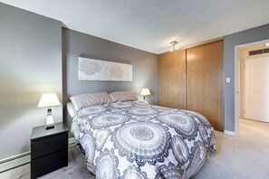 Ein Schlafzimmer mit einem Bett, zwei Nachttischen, einem Wandbild, einem Kleiderschrank und einer Tür.