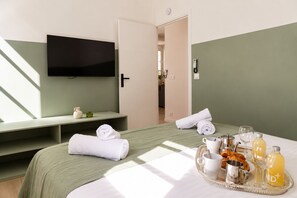 A hotel room with a bed, a television, a tray with breakfast items, and a bathroom visible through an open door. - TheBlueStay 369 - Beautiful A/C Apartment in Paris (Paris)