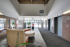 Eine Hotelhalle mit einer Rezeption, einer Sitzecke und Blick auf die Straße.