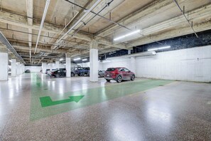 Eine mehrstöckige Parkgarage mit Betonpfeilern, Neonbeleuchtung und Richtpfeilen auf dem Boden.
