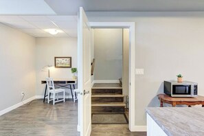 Una habitación con escritorio, silla y microondas sobre una mesa.