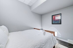Un dormitorio con cama, un cuadro enmarcado en la pared y un tragaluz.