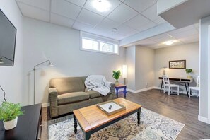 A living room with a sofa, coffee table, and a desk area with a chair.