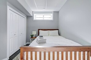 Un dormitorio con una cama, una mesita de noche, un ventanal y un armario.