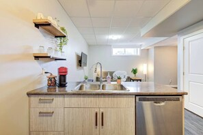 Una cocina moderna con lavavajillas integrado, pileta de acero inoxidable y muebles de madera.