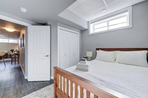 A bedroom with a wooden bed, white bedding, a skylight, and a white wardrobe. - The Arlo - North Park Gem Close to Spadina! (Saskatoon)