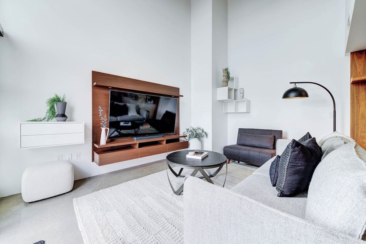 A modern living room with a flat-screen TV, a sofa, a coffee table, and a floor lamp.