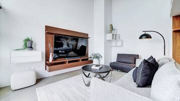 A modern living room with a flat-screen TV, a sofa, a coffee table, and a floor lamp.