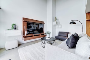 Un salon moderne avec un téléviseur à écran plat, un canapé, une table basse et un lampadaire.