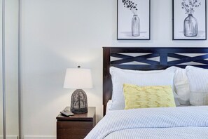 A neatly made bed with striped bedding and a headboard with a crisscross pattern. - The Tuscany - Located Downtown! (Saskatoon)