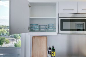 Une cuisine équipée d’un four à micro-ondes encastré, de boîtes de rangement transparentes et d’une planche à découper en bois.