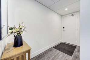 Un couloir avec une table en bois et un vase de fleurs, un tapis sombre et une porte blanche.