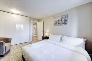 Ein Hotelzimmer mit einem Bett, einem Sessel, einem Kleiderschrank und einem Gemälde an der Wand.