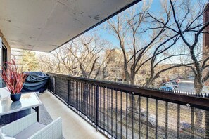 Ein Balkon mit Blick auf nackte Bäume und geparkte Autos.