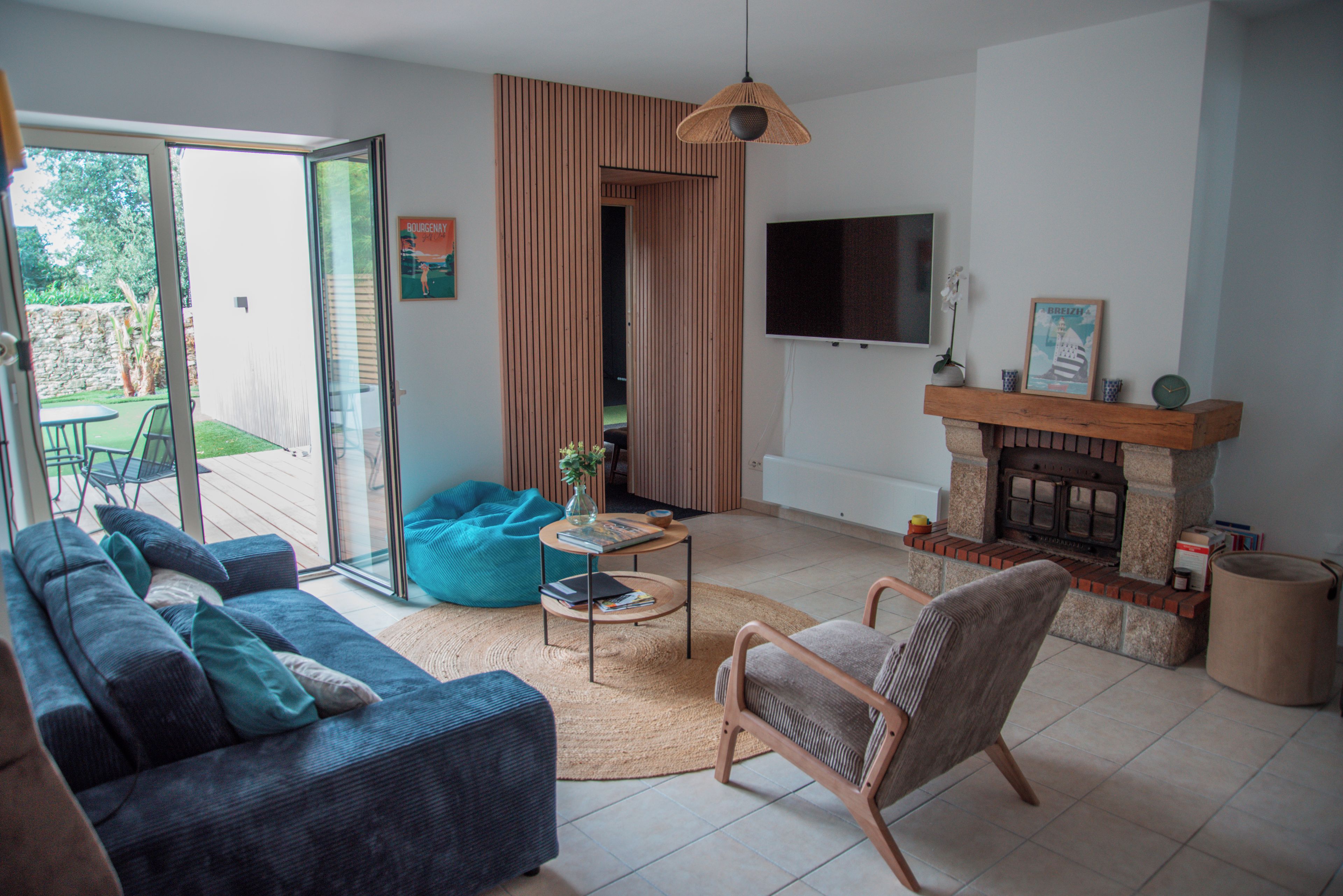 Ein Wohnzimmer mit Sofa, Sessel, Couchtisch und Kamin.
