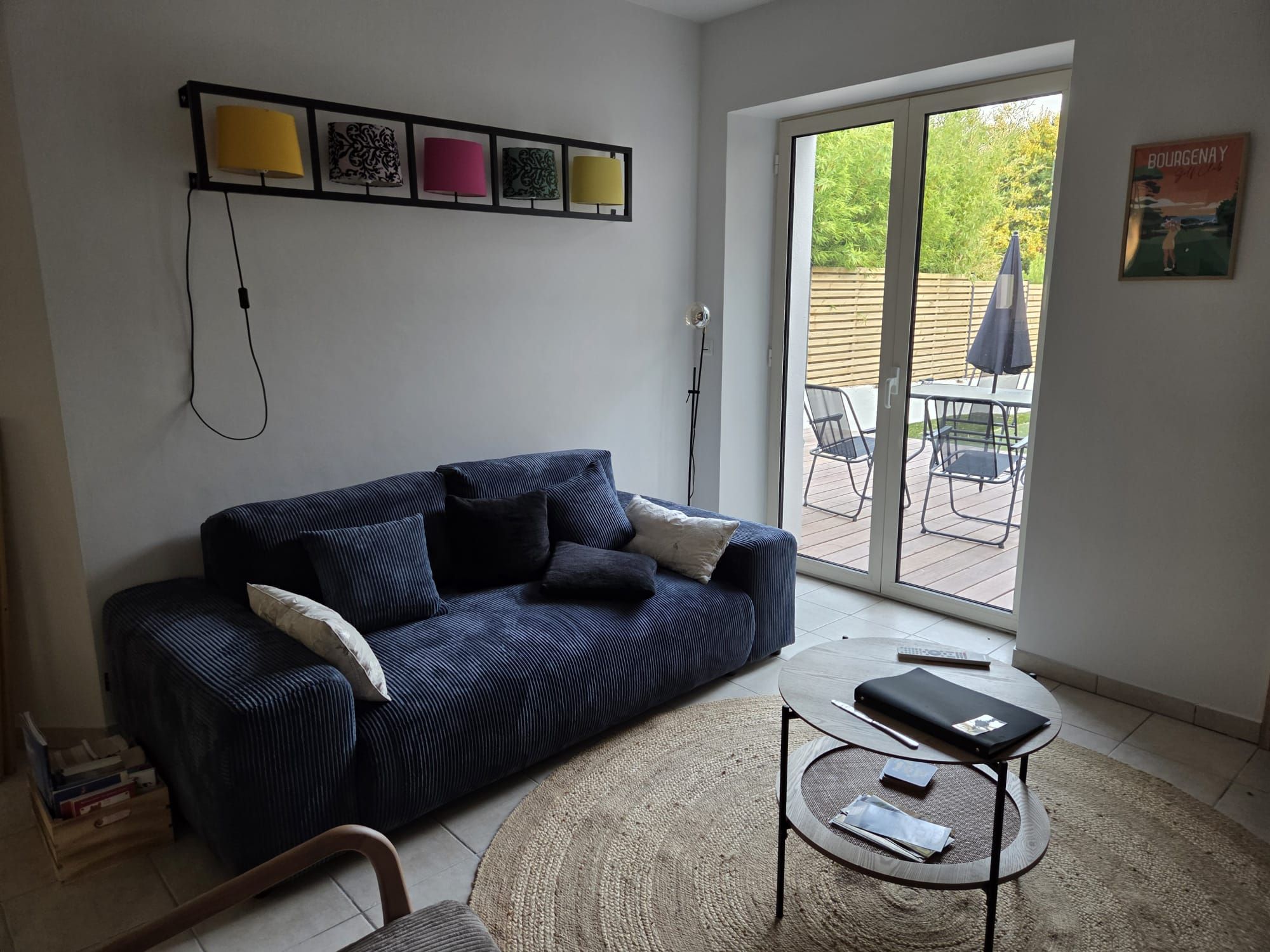 Ett vardagsrum med en mörkblå soffa, ett runt soffbord och en stor skjutdörr i glas som leder ut till en uteplats.