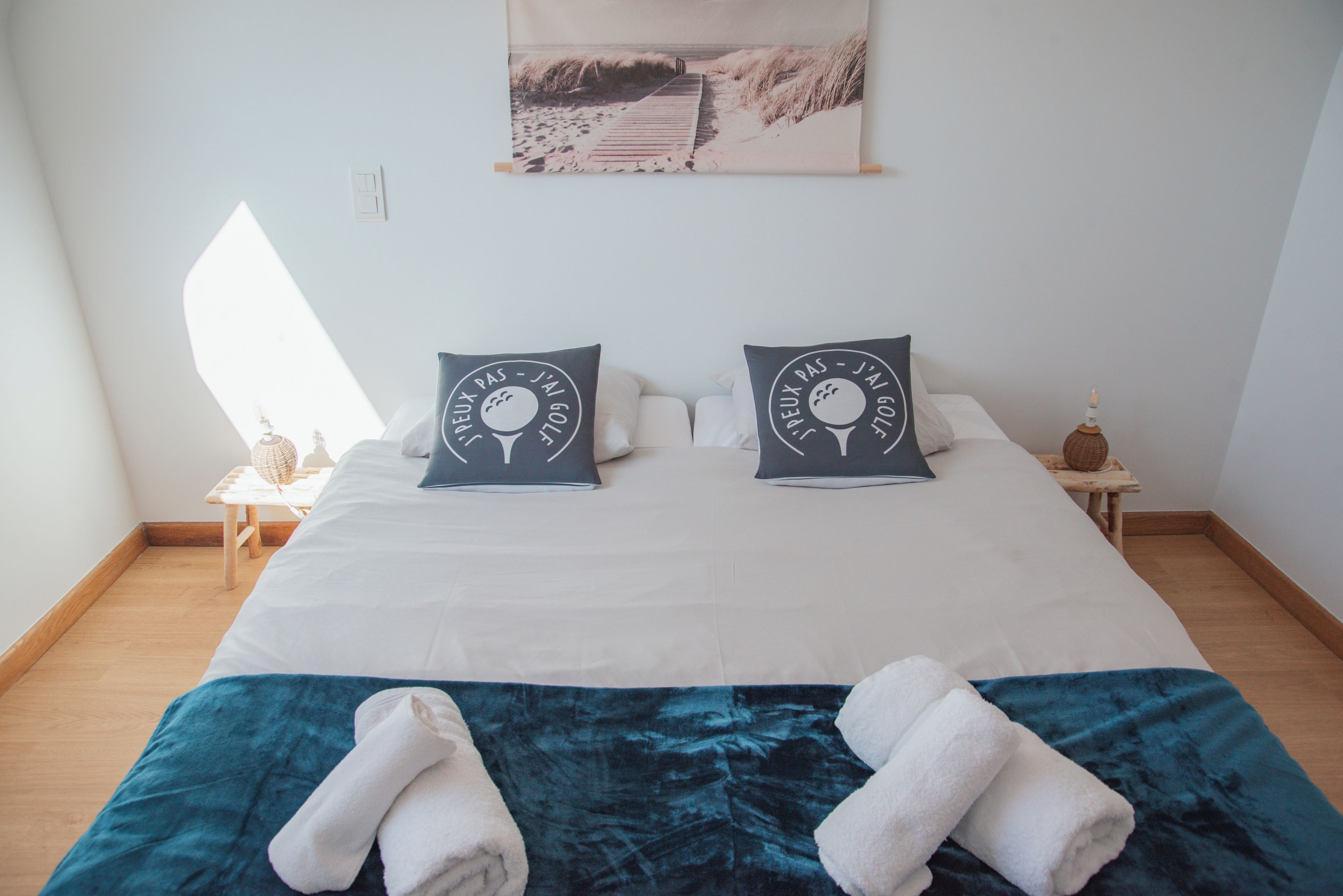 Ein ordentlich bezogenes Bett mit zwei Kissen, einer blauen Decke und zwei Handtüchern.