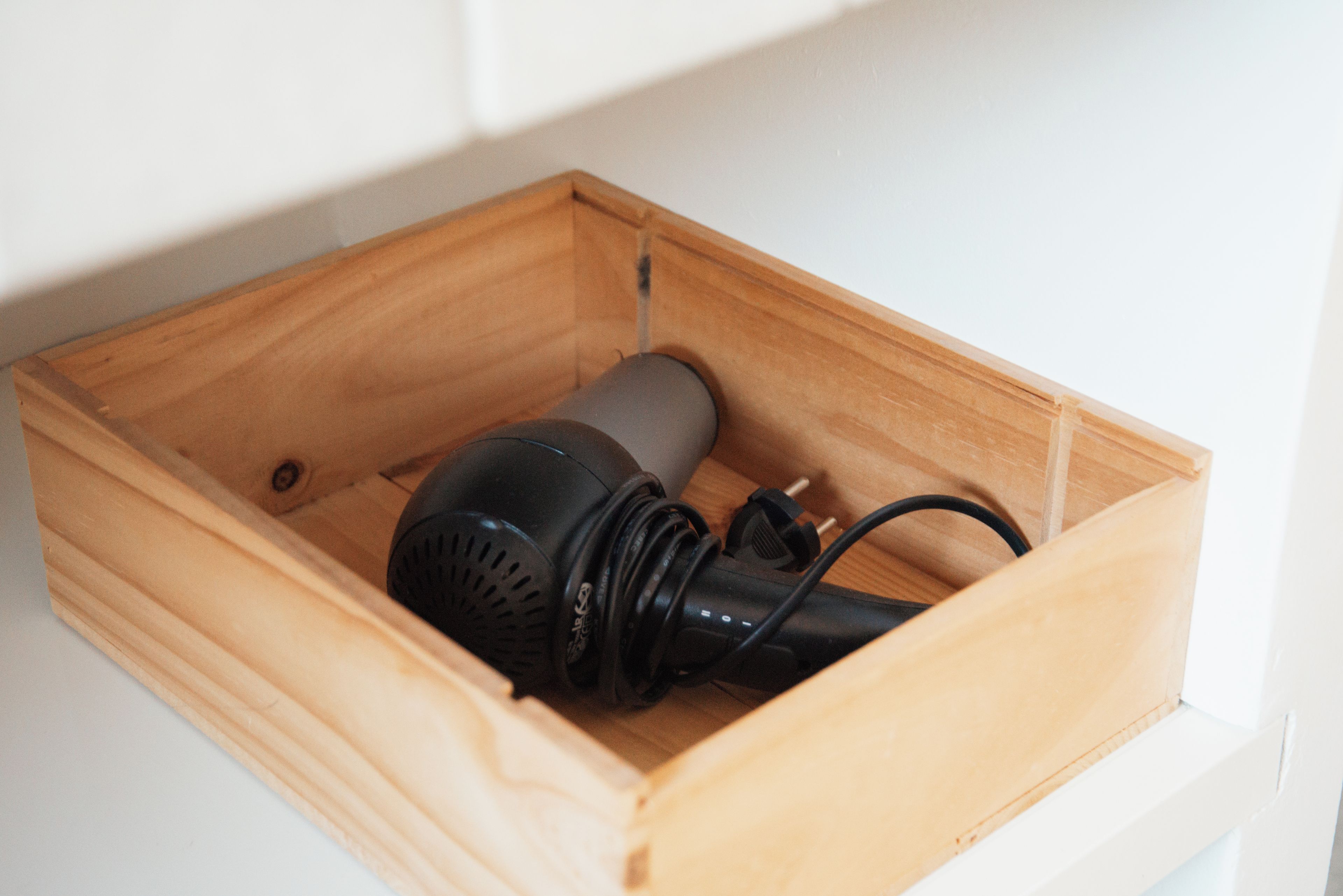 Een houten lade met een zwart elektronisch apparaat erin.
