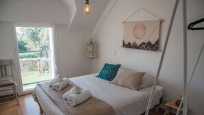 Et soveværelse med en seng, et vindue og en lampe på væggen.