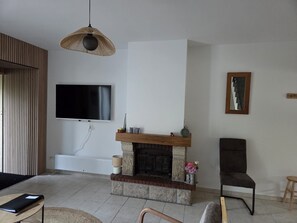 A living room with a fireplace, a television mounted on the wall, and a wooden slatted wall.